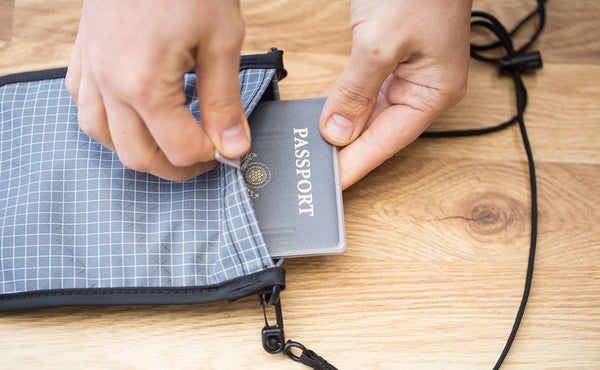 A person inserting a US Passport into a Passport Pouch.